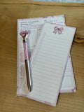 Set of stationery items including a pen and lined paper on a wooden surface. PINK COQUETTE. PINK BOW. daily planner
